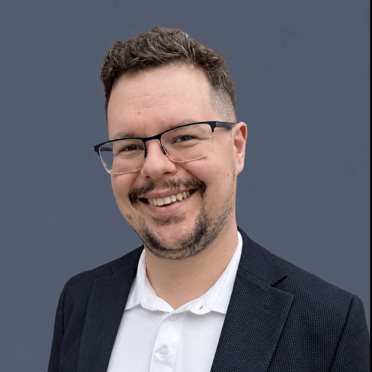 Matej Poljanic smiling, wearing glasses and a navy jacket
